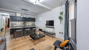 Eine moderne Küche mit Kochinsel, Barhocker, Esstisch und Wand-Fernseher.