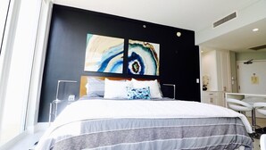 Een moderne hotelkamer met een groot bed, een zwart accentmuur en twee abstracte schilderijen.