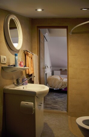 A bathroom with a sink, mirror, towel rack, and shower.