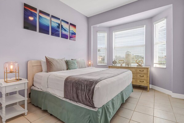 A bedroom with a bed, bedside tables, a dresser, and a window with blinds.
