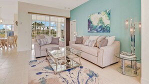 A living room with a beige sofa, a glass coffee table, and a teal accent wall. - 1226 SE 20th ST (Cape Coral)