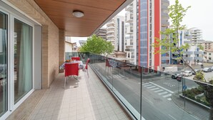 Een balkon met een tafel en stoelen, met uitzicht op een straat met auto's en gebouwen.