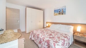 Een slaapkamer met een bed, nachtkastjes, een houten kledingkast en een schilderij aan de muur.