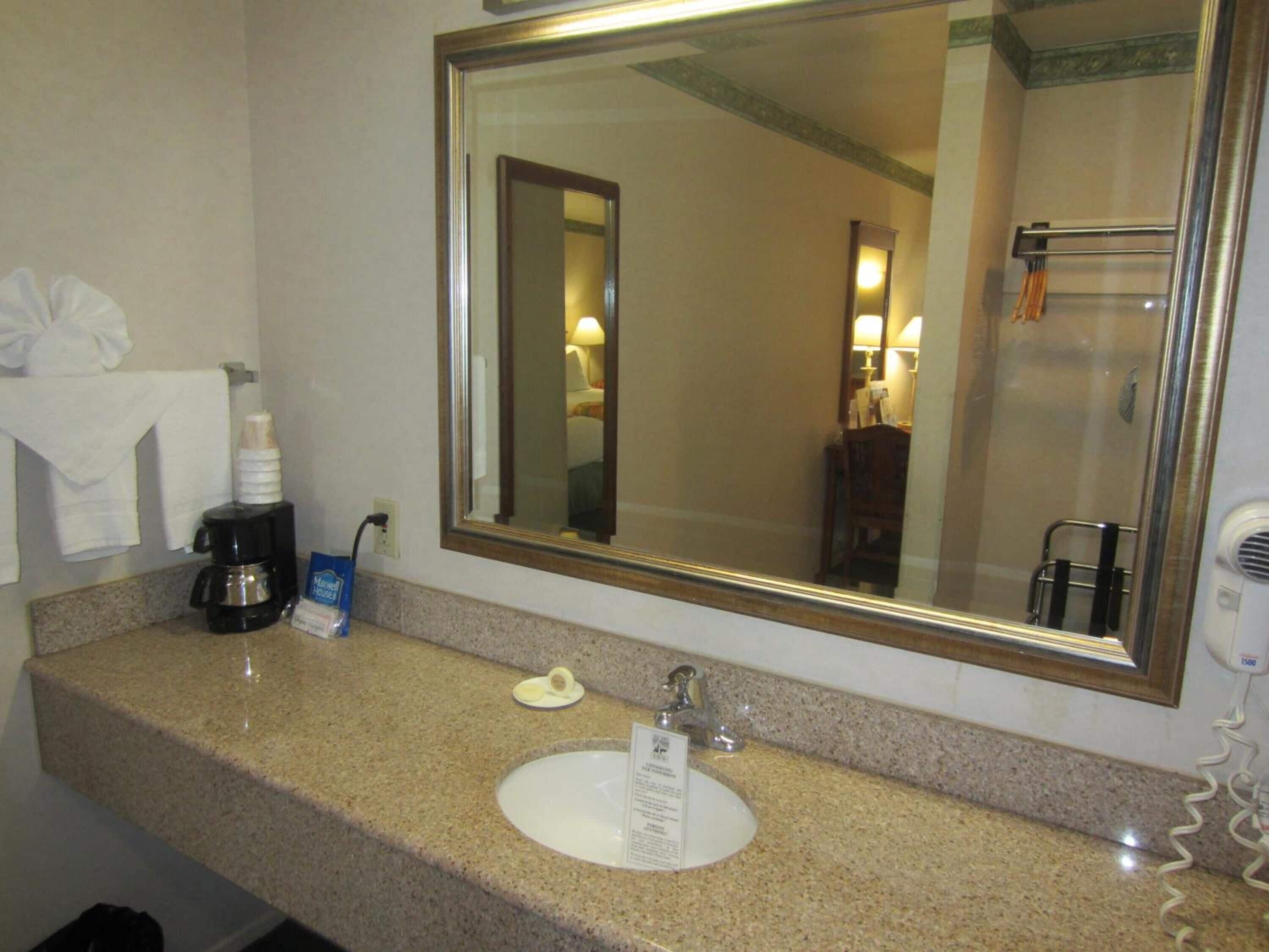 A bathroom with a sink, mirror, and towel rack.