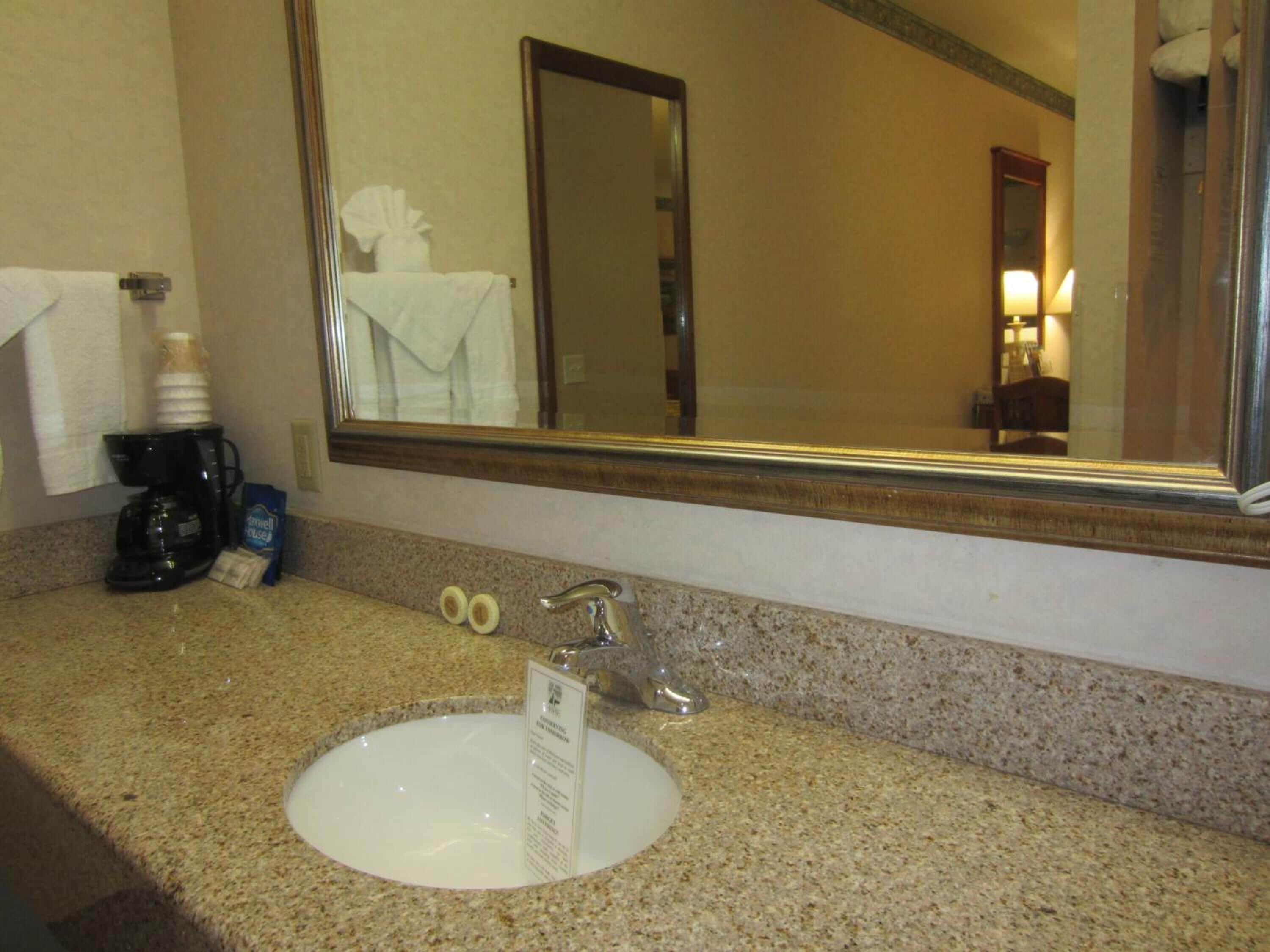 Een hotelbadkamer met een wastafel, een koffiezetapparaat en een handdoekhouder.