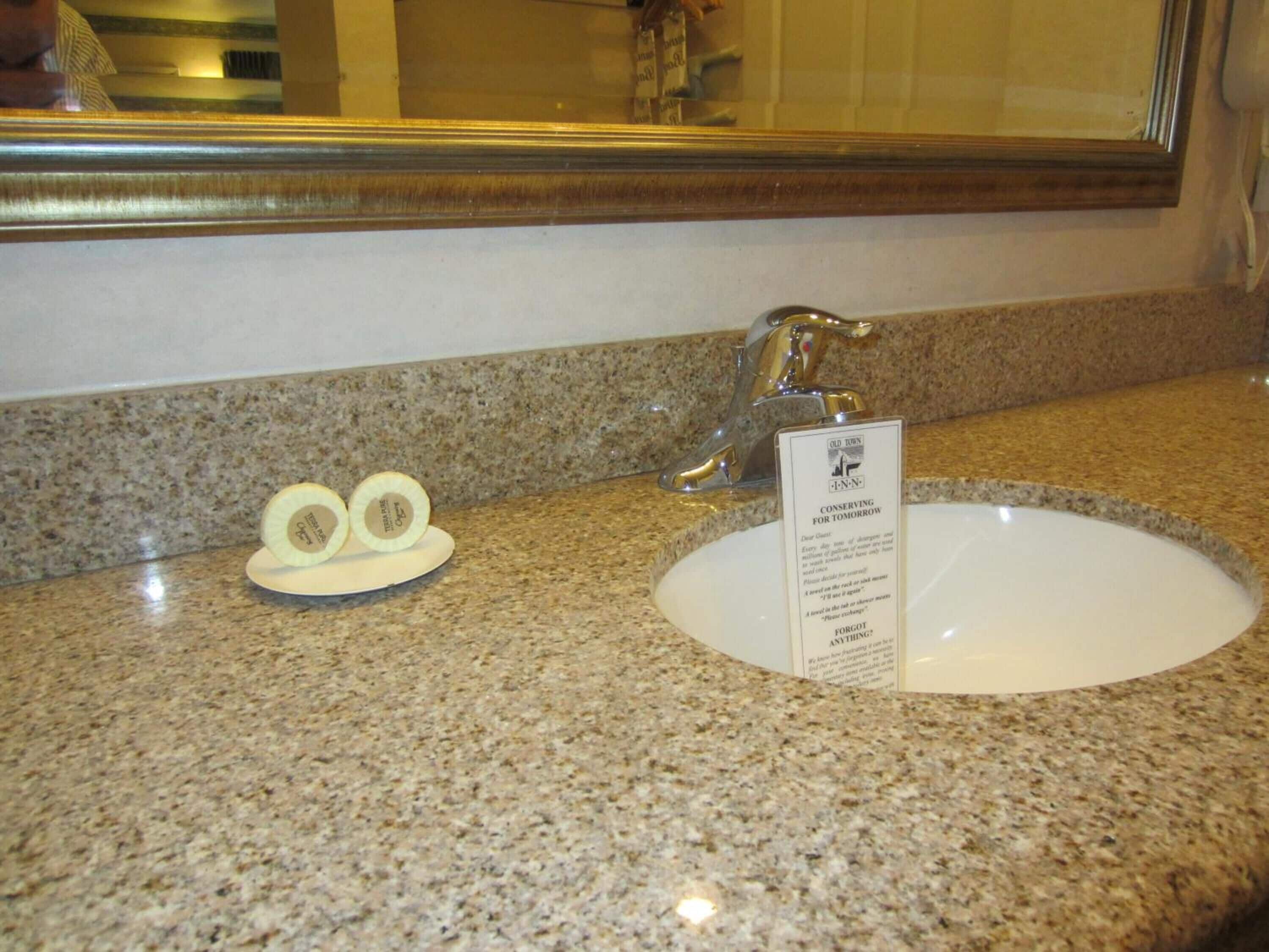 Una encimera de granito con un lavabo y un espejo.