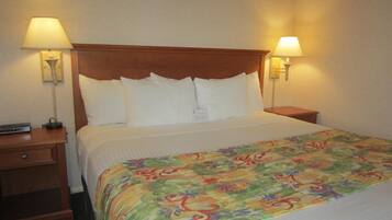 A hotel room with a wooden headboard, white bedding, and two bedside lamps.