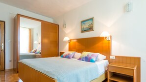 Quarto com cama, mesas de cabeceira, guarda-roupa e um quadro na parede.