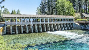 A long, narrow building with a flat roof, supported by multiple piers extending into a river. - Lake Tahoe’s Ultimate Family & Friends Retreat (Olympic Valley)