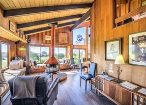 A spacious room with a large window, a fireplace, and a seating area with a sofa and chairs.
