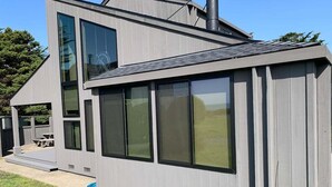 Ett modernt hus i två våningar med stora fönster och en täckt uteplats.