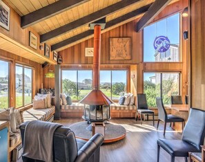 A cozy interior with a fireplace, seating area, and large windows offering a view.