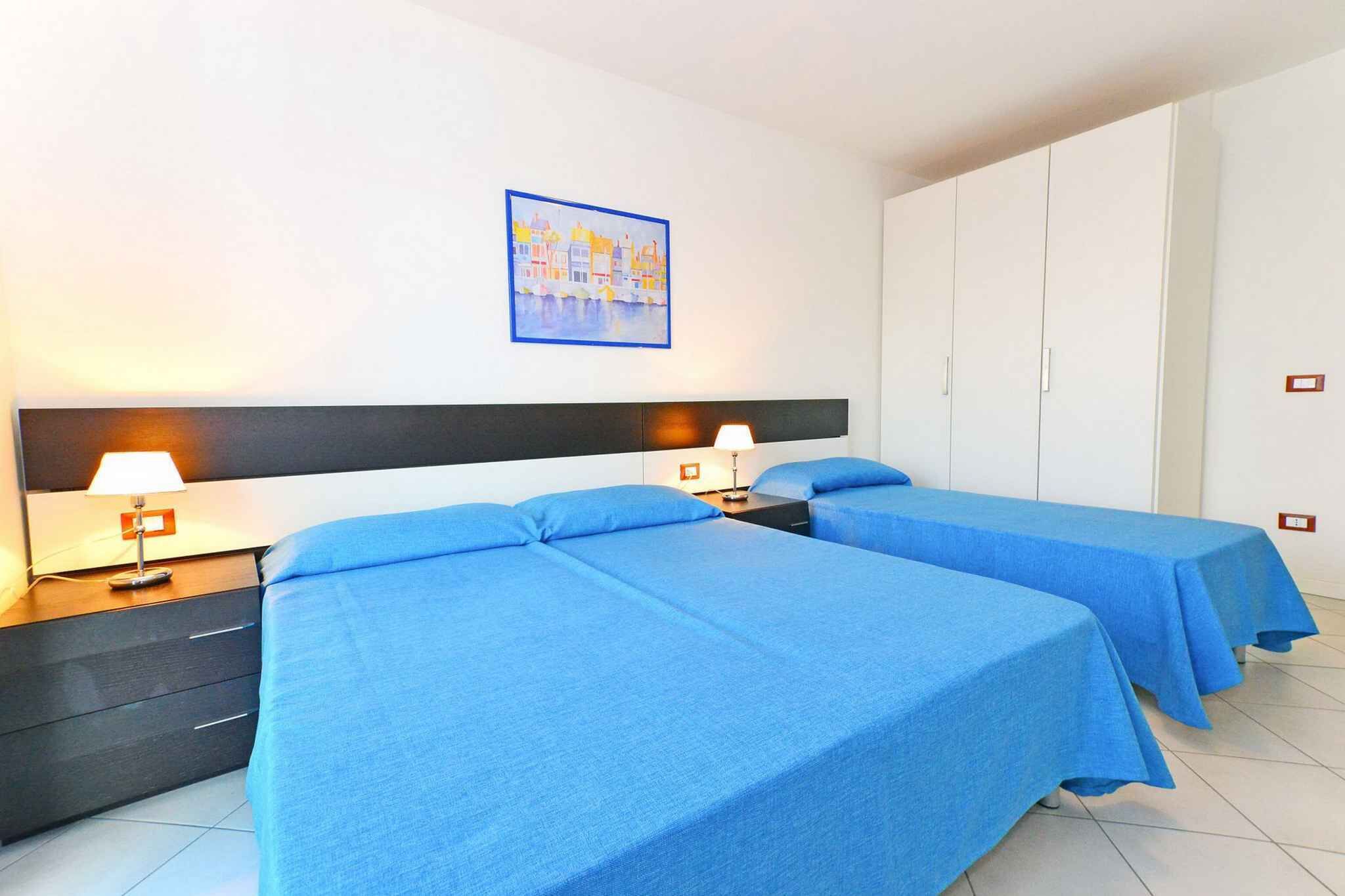 Une chambre d’hôtel avec deux lits, une table de chevet avec des lampes, une armoire et un tableau au mur.