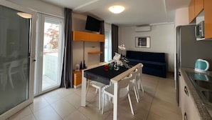 A modern kitchen with a dining area, a built-in oven, and a large window.