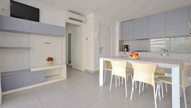 A modern kitchen with a white countertop, four chairs, and a dining table.