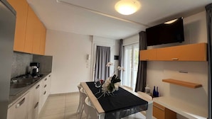 A modern kitchen with a dining table, chairs, and a TV mounted on the wall.