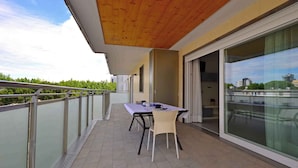 A balcony with a table and chairs, a glass door, and a view of the city.