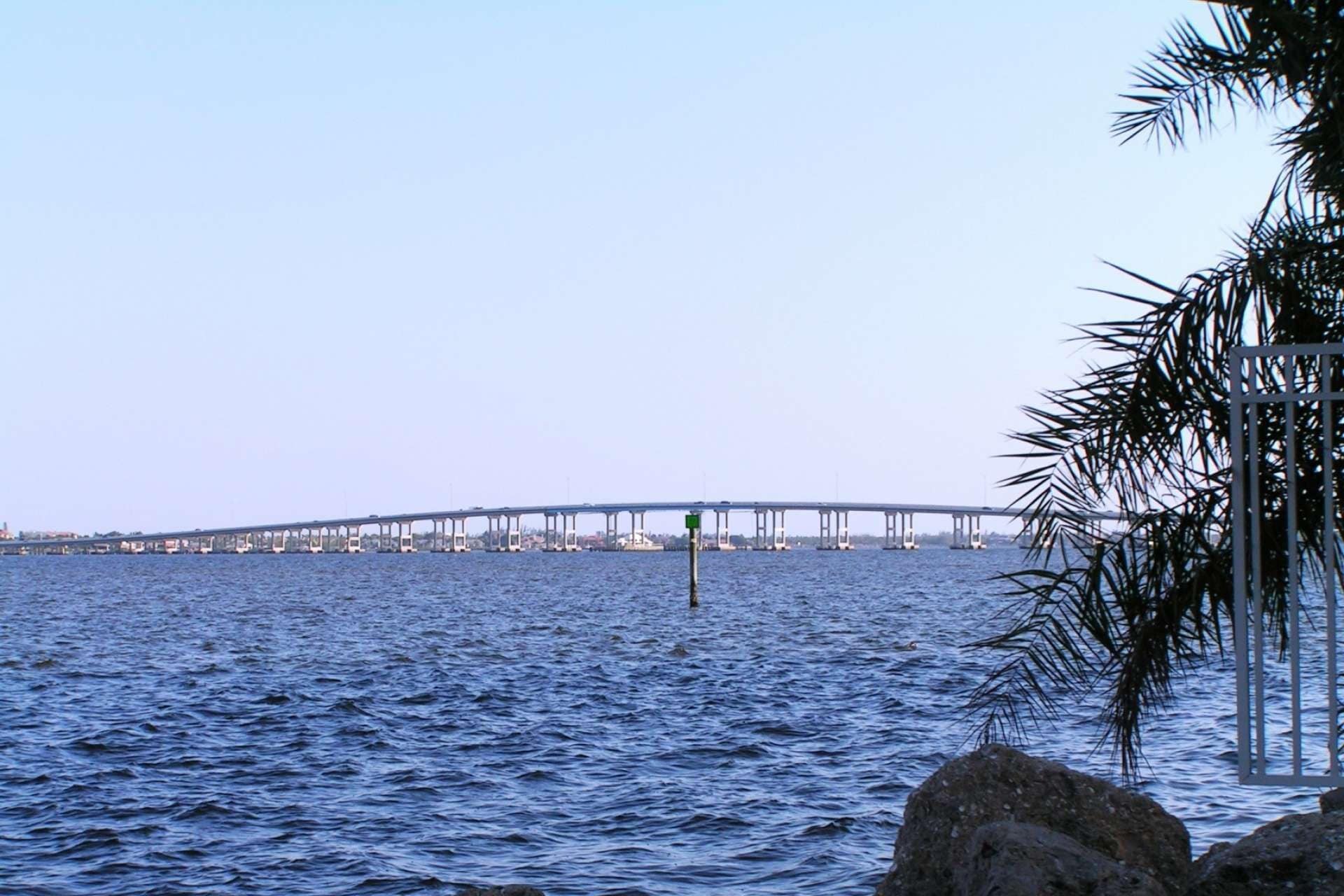 Un pont enjambant une étendue d’eau, offrant une vue dégagée sur les bâtiments de la ville en arrière-plan.