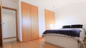 Un dormitorio con cama, armario de madera y una puerta.