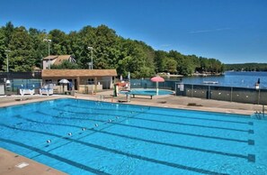 Swimmers can enjoy the pool surrounded by a fence, adjacent to a body of water.