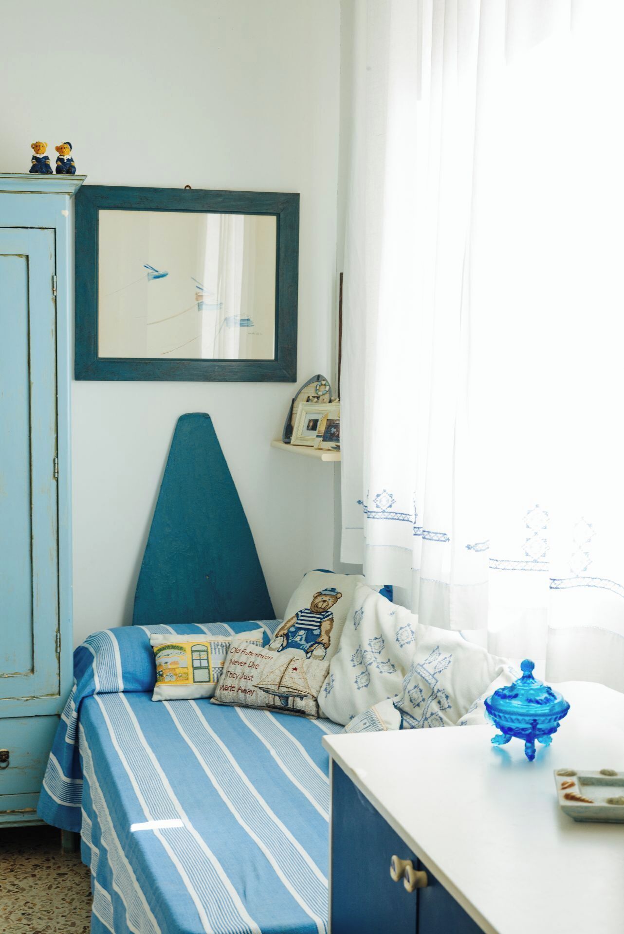 A bedroom with a bed, a dresser, a window with curtains, and a wall-mounted picture.