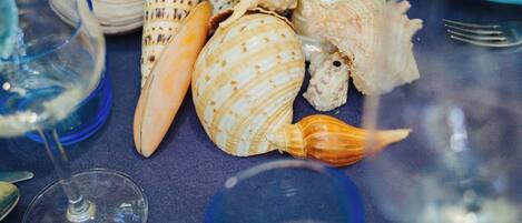 A table set with various seashells, blue glassware, and matching blue plates.