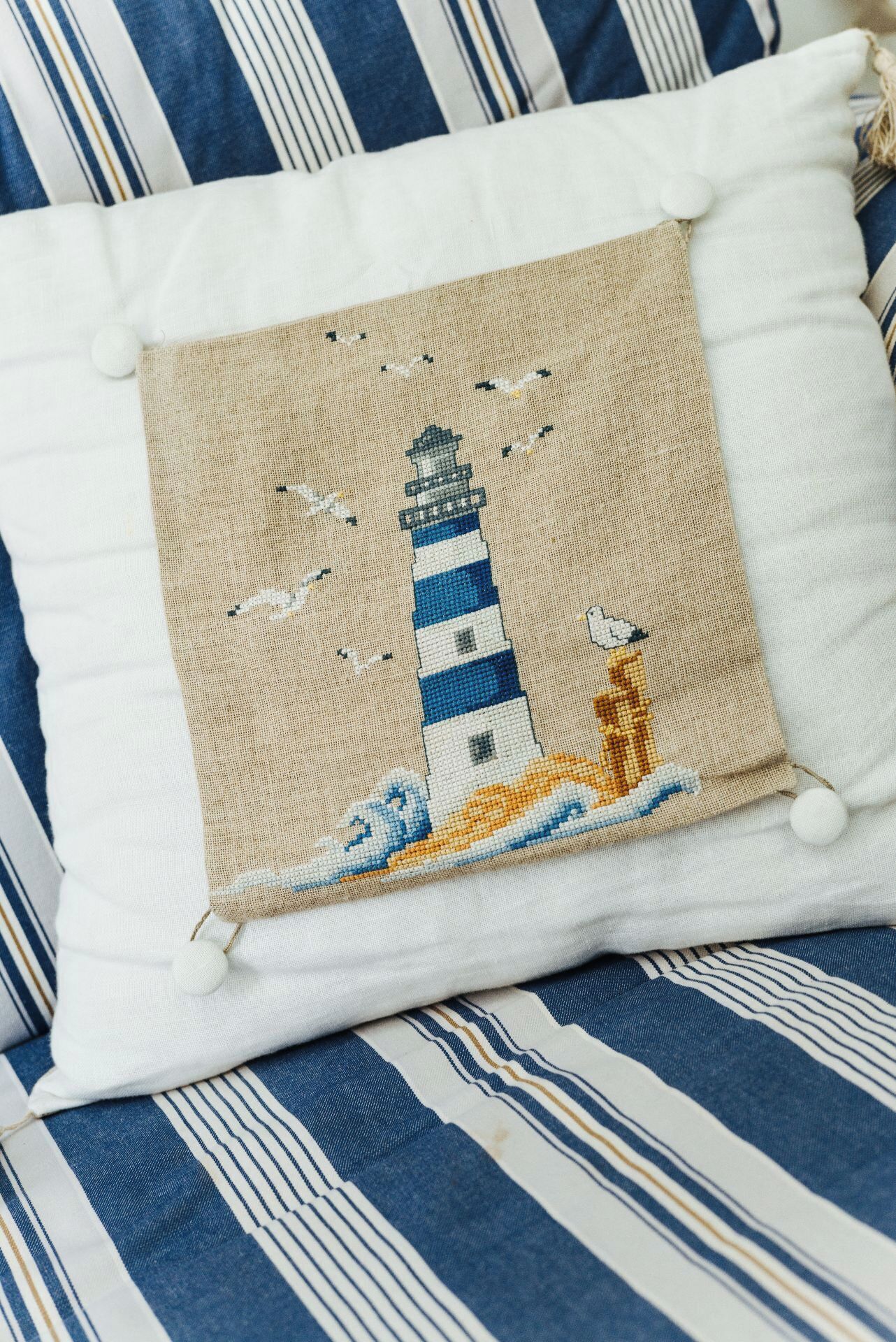 Un cuscino con un disegno di un faro su un tessuto a righe.