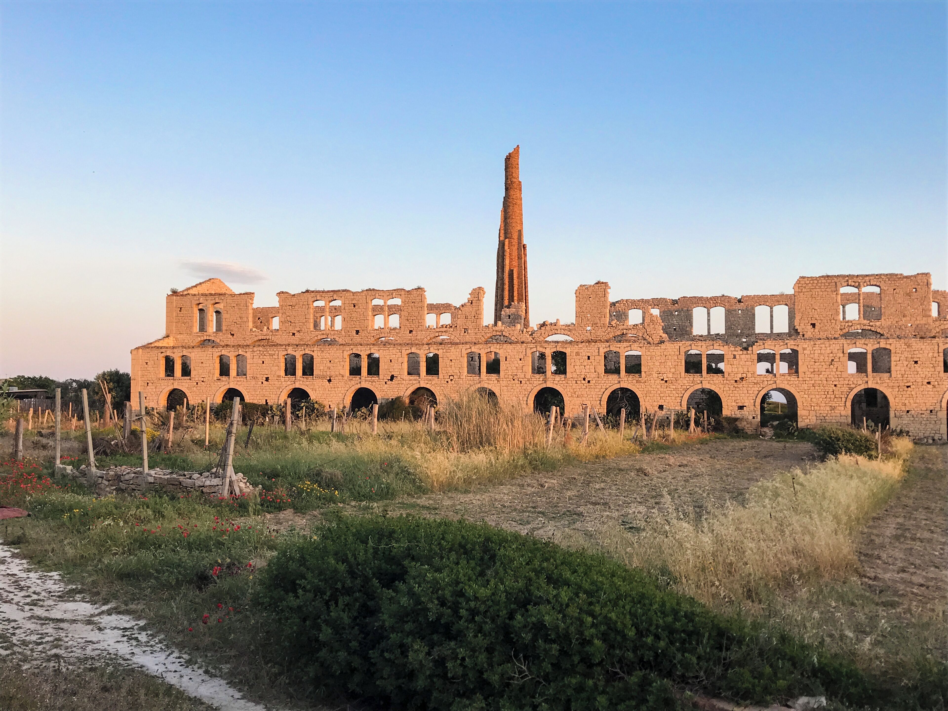 Un edificio abandonado con múltiples arcos y una torre alta.