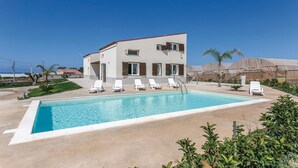 A modern building with a swimming pool, white lounge chairs, and palm trees. - Nice home in Ragusa with private swimming pool, can be inside or outside (Ragusa)