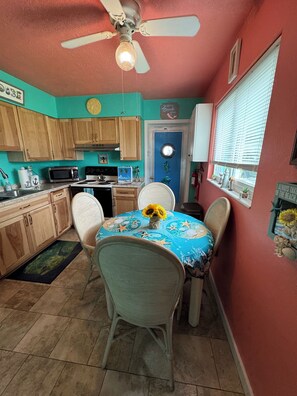 Una cocina con armarios de madera, microondas, estufa y ventilador de techo.