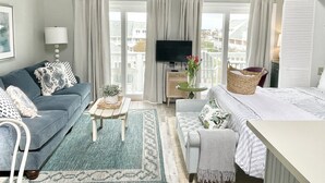 Une chambre d’hôtel avec un canapé, une petite table, un lit, une télévision et une vue sur l’extérieur.