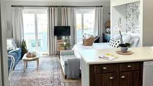 Un salon moderne avec un téléviseur, un canapé et une table basse. Il y a également un coin cuisine avec des meubles en bois et une table à manger.