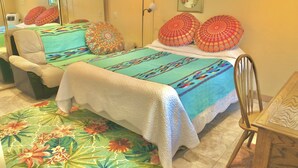 A hotel room with a bed, a chair, a desk, a mirror, and a picture on the wall. - Prescott Paradise! Sunroom Suite in the Heart of the Granite Dells! (Prescott)
