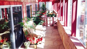 A covered patio area with potted plants and a stone floor. - Prescott Paradise! Sunroom Suite in the Heart of the Granite Dells! (Prescott)