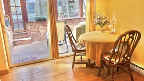 A dining area with a table, chairs, and a view through a glass door to an outdoor patio. - Prescott Paradise! Sunroom Suite in the Heart of the Granite Dells! (Prescott)