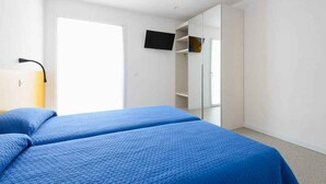 Une chambre avec deux lits, une télévision et une armoire.