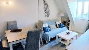 Een gezellige, goed verlichte kamer met een eettafel, een bank en een klein wit tafeltje.