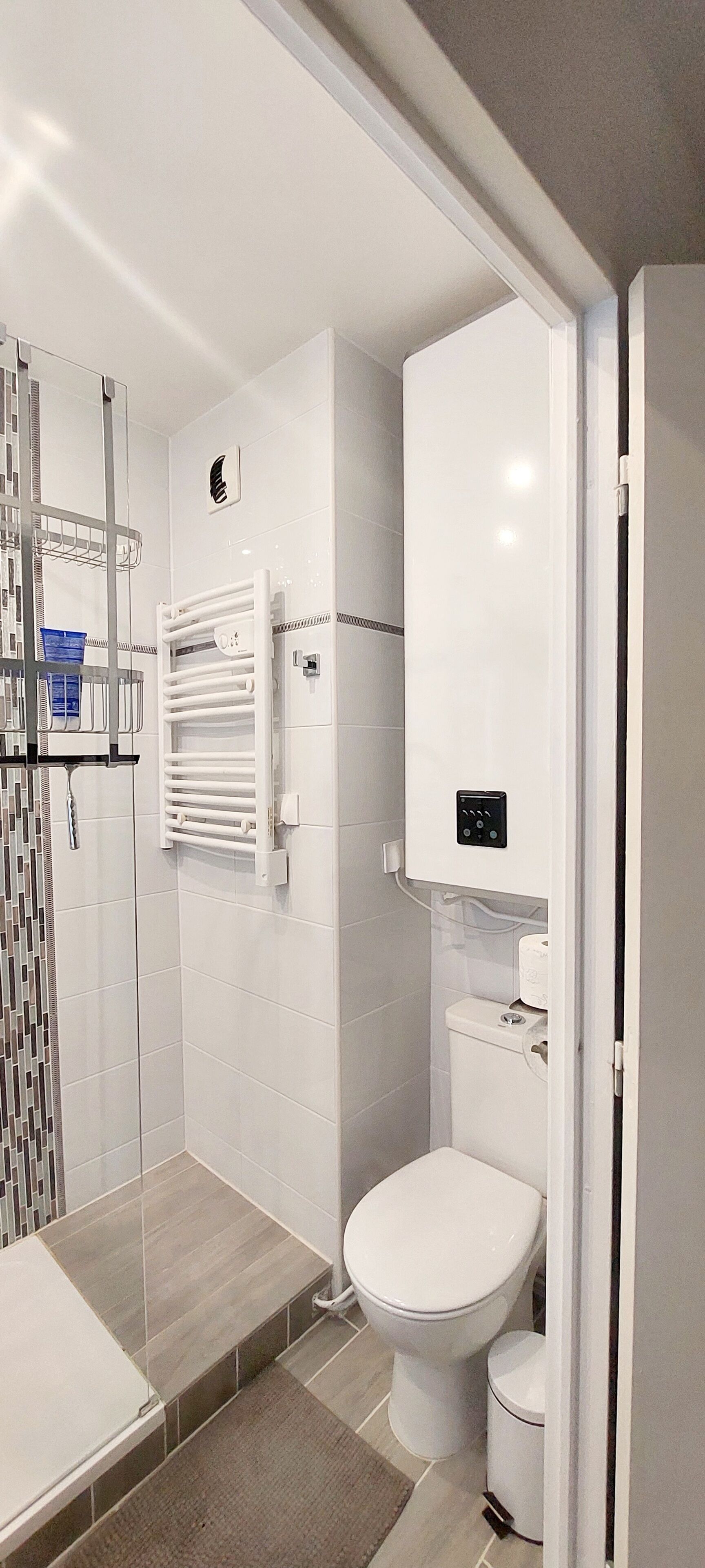 Een moderne badkamer met een douchecabine van glas, een wit toilet en een ingebouwde verwarming.