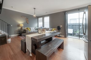 A modern living room with a wooden bench, a sofa, and a dining table. - Centrally Located SOHO Retreat Walkable to UT & Dining (Tampa)