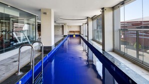 A long indoor swimming pool with clear glass walls on one side and a bench in the center. - Swainson at Embassy - 917 (Adelaide)