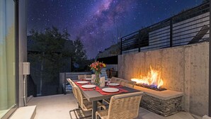 An outdoor dining area with a fire feature and a starry night sky.