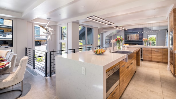 A modern kitchen with a large island, stainless steel appliances, and a view of the outdoors.