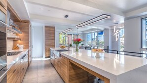 A modern kitchen with a large island, wooden cabinetry, and a view of the outdoors.