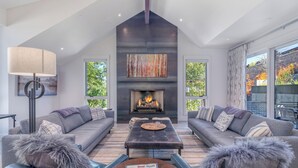 A modern living room with a fireplace, grey sofas, a coffee table, and a magazine on the table.