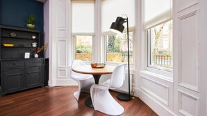 Un comedor con una mesa redonda, sillas blancas y una lámpara de pie negra.