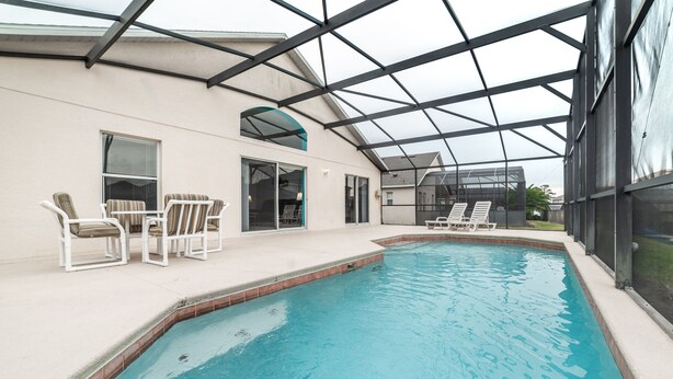 An indoor swimming pool with clear blue water, surrounded by white lounge chairs and a covered patio area. - ✨ Great Value 3BR Villa w/ Private Pool & Game Room near Disney 🏝️🎢 (Kissimmee)