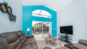 A living room with a brown leather sofa, a glass coffee table, and a flat-screen TV. - ✨ Great Value 3BR Villa w/ Private Pool & Game Room near Disney 🏝️🎢 (Kissimmee)