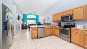 A modern kitchen with stainless steel appliances, wooden cabinets, and a large island. - ✨ Great Value 3BR Villa w/ Private Pool & Game Room near Disney 🏝️🎢 (Kissimmee)