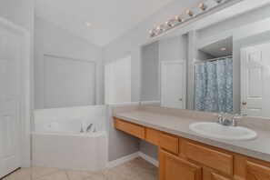 Ein modernes Badezimmer mit einer Badewanne, einem Waschbecken und einem groĂen Spiegel.