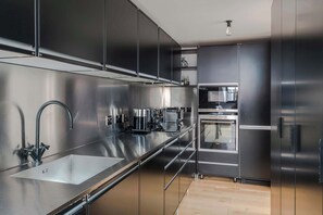 Una cocina moderna con electrodomésticos de acero inoxidable, un lavamanos doble y un horno empotrado.